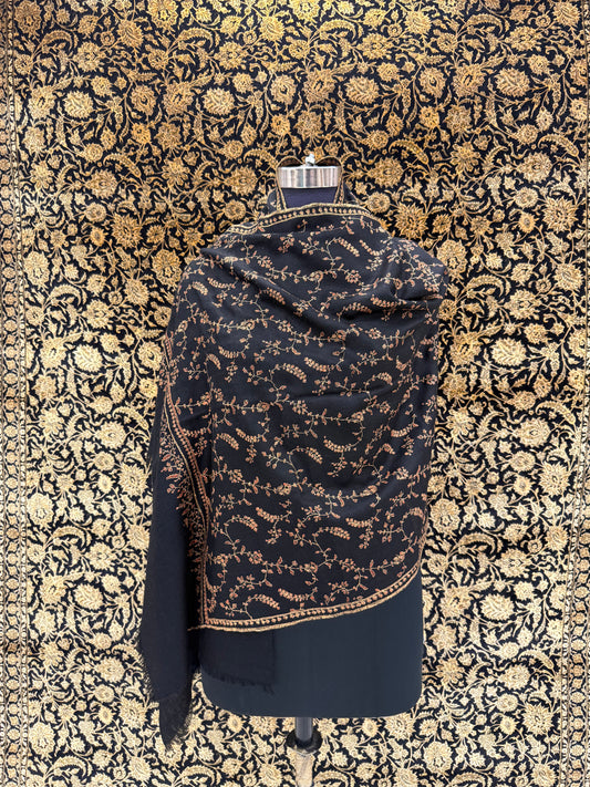 Black and gold patterned fabric on a mannequin against a floral patterned wall.