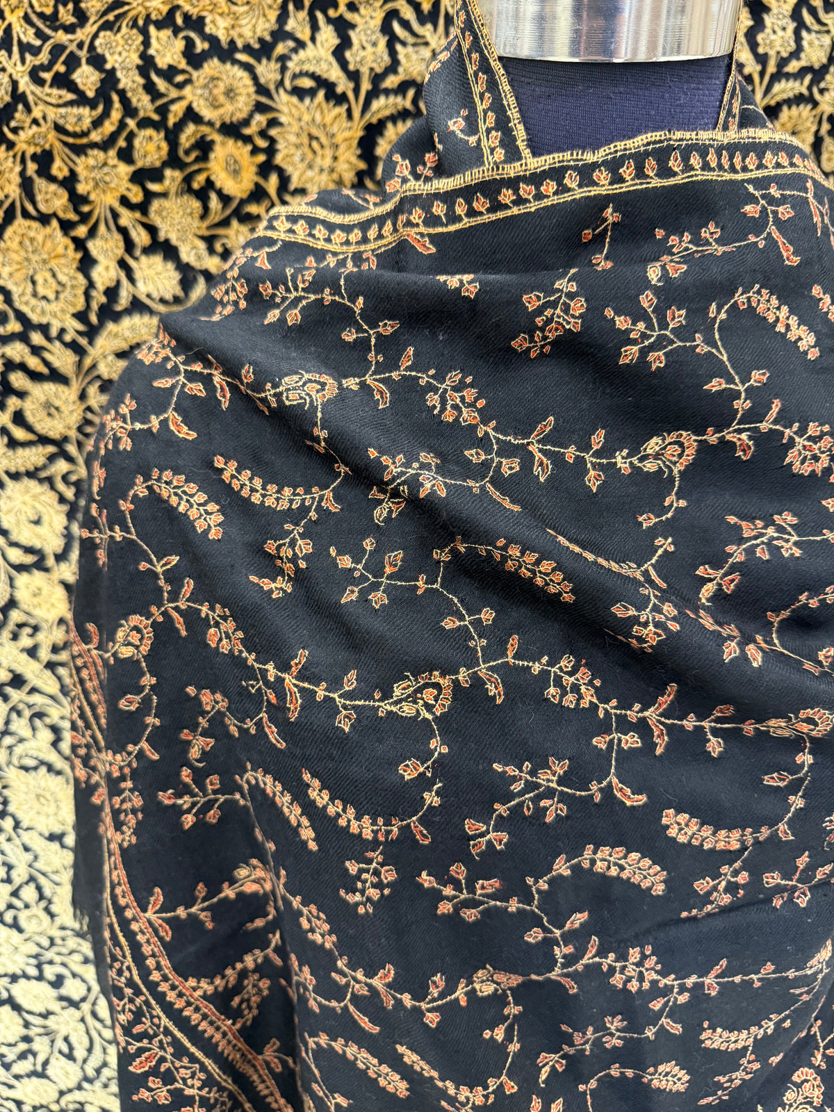 Black fabric with gold embroidery on a patterned background