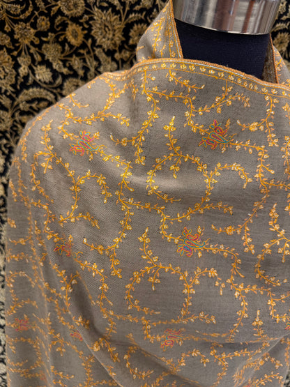 Gray fabric with gold embroidery on a mannequin against a dark floral background