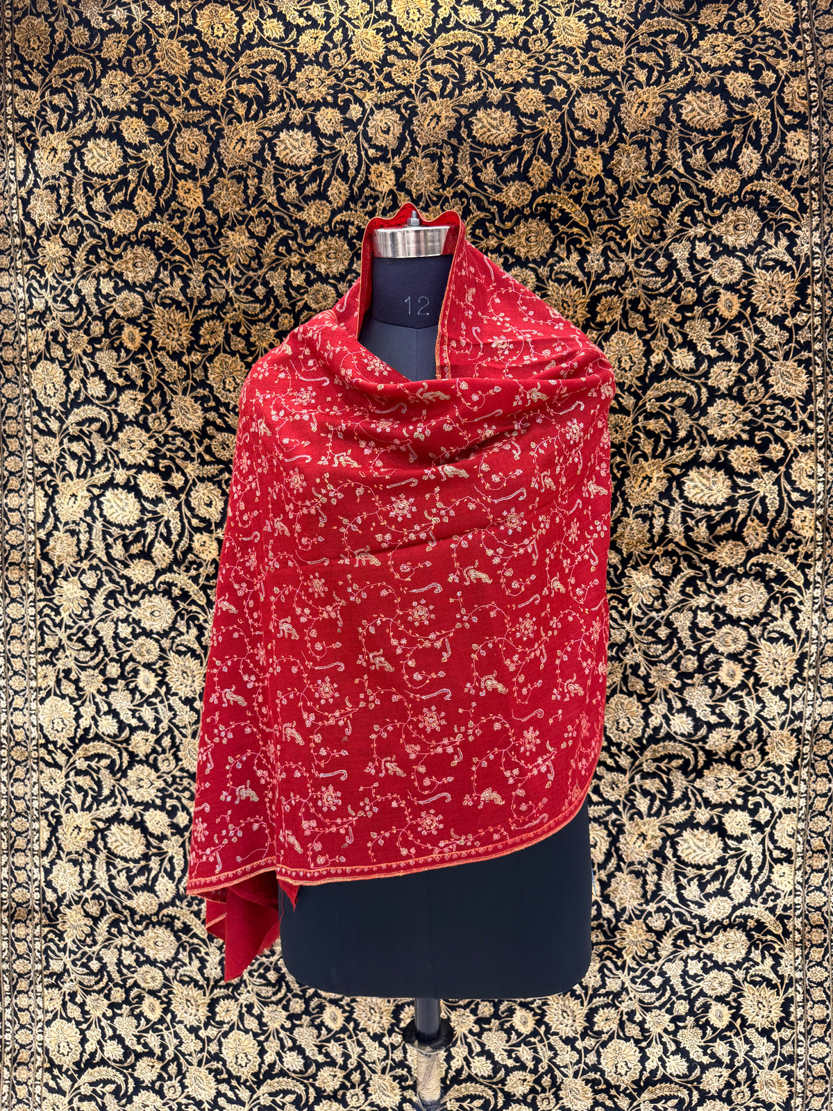 Red patterned scarf draped over a black garment on a floral-patterned background