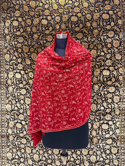 Red patterned scarf draped over a black garment on a floral-patterned background