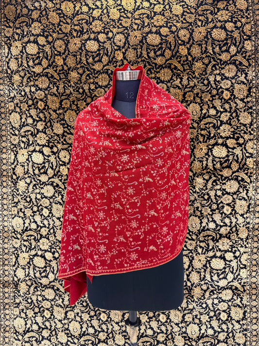 Red patterned scarf draped over a black garment on a floral-patterned background