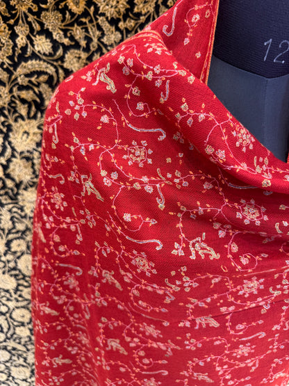 Close-up of a red fabric with intricate white patterns on a textured background