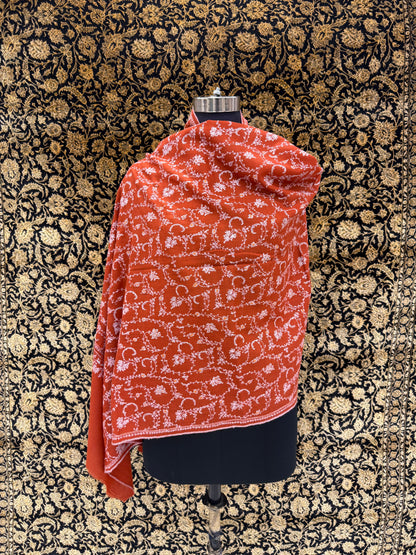 Red patterned fabric draped over a mannequin against a decorative black and gold background